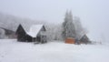 Fantastic winter landscape with glowing wooden house against the backdrop of glowing city lights in fog. Cozy cabin in Carpathian Royalty Free Stock Photo