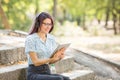Beautiful young girl studying on a tablet on a park background. Self-education concept. Copy space. Royalty Free Stock Photo