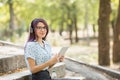 Beautiful young girl studying on a tablet on a park background. Self-education concept. Copy space. Royalty Free Stock Photo