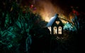 Fantasy decorated photo. Small beautiful house in grass with light. Old house in forest at night with moon. Selective focus Royalty Free Stock Photo