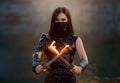 Fantasy fighting woman assassin holds in hands burning daggers. Red-haired girl warrior in black leather costume. ninja