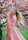 Fantasy happy woman princess walks in spring blooming garden hugs herself by shoulders. Pink flowers sakura tree summer Royalty Free Stock Photo