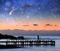 Fantasy landscape - silhouette of a woman walking on pier admiring stars in the sky.