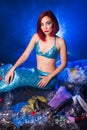 Fantasy mermaid in deep ocean shocked because water pollution. Plastic water bottles and bags pollution on sea floor Royalty Free Stock Photo