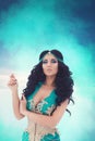 Fantasy portrait of a beautiful tanned brunette girl in a turquoise Oriental dress and jewelry Royalty Free Stock Photo