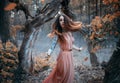 Fantasy portrait of a young red-haired woman in the autumn forest. The nymph girl runs and looks around. Long hair Royalty Free Stock Photo