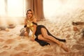 fantasy sexy woman lying posing in room full sand desert. clothes gold accessories beauty face. fashion model girl queen Royalty Free Stock Photo
