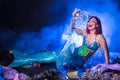 Fantasy stupid mermaid in deep ocean. Plastic water bottles and bags pollution on sea floor. Environmental problem.