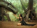 Fantasy woman elf queen touching with hands dragon head. Girl mistress tamed monster concept female power. black