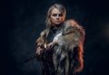 Fantasy woman knight wearing cuirass and fur, holding a sword scabbard ready for a battle. Fantasy fashion. Cosplayer as Royalty Free Stock Photo