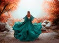 Fantasy woman queen red hair runs in autumn forest. Girl in long elegant royal evening vintage green dress. silk fabric Royalty Free Stock Photo