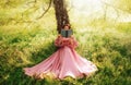 Fantasy woman sits under tree holding romantic book in hands reading novel. Pink long vintage dress Fairy princess girl Royalty Free Stock Photo