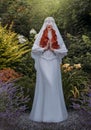 Fantasy woman in white vintage dress holy virgin prays face is hidden by silk veil. Red-haired girl nun queen. Medieval