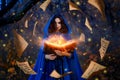 Fantasy woman witch magician in hood holds in hands magic book, bright orange light spells, wind scatters fall sheets