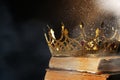 Fantasy world. Beautiful golden crown and old books lit by magic light on table Royalty Free Stock Photo