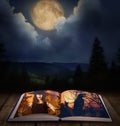 Fantasy world. Open book of fairytales with witch and black crow on pages Royalty Free Stock Photo