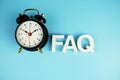 FAQ alphabet letters with alarm clock top view on blue background Royalty Free Stock Photo