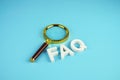 FAQ alphabet letters with magnifying glass on blue background Royalty Free Stock Photo