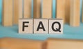 FAQ Frequently Asked Questions abbreviation written on wooden blocks on a blue background Royalty Free Stock Photo