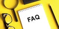 FAQ on a notebook with glasses, magnifier and pensil