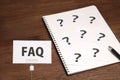 FAQ on a piece of paper and many question marks on notebook. Royalty Free Stock Photo