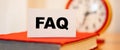 FAQ on white paper with clock background. Knowledge on remote online education Royalty Free Stock Photo