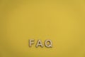 FAQ wood letters searching for facts truth news answers concept copy space flat lay on muted yellow