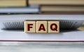 FAQ - word on wooden cubes against the background of the open book