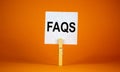 FAQS, frequently asked questions symbol. White paper on wooden clothespin. Words `FAQS, frequently asked questions`. Beautiful