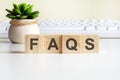 FAQS word made with wooden blocks on background white keyboard