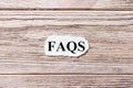 FAQS of the word on paper. frequently asked questions concept. Words of FAQS on a wooden background