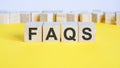 faqs word on wooden building blocks lying on the yellow table, concept