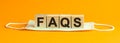 Faqs word written on wood block. faqs text on table, concept. yellow background