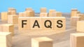 faqs - word is written on wooden cubes close-up. bright blue background, financial business concept