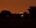 Far off tower with lights in the dark night time sky silhouettes Royalty Free Stock Photo