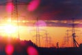 Far-reaching power lines against the backdrop of a bright setting sun with rays and highlights. The effect of an old color film Royalty Free Stock Photo