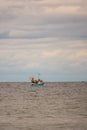 on the sea floats a fishing boat, which is surrounded by many seagulls and the sky is full of clouds Royalty Free Stock Photo