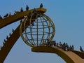 Far view of pigeons sitting on a stella in the form of a ball against a blue sky