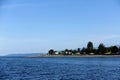 A faraway view from the ocean of a beautiful community of homes right along the beach surrounded by sea and trees, in Powell River