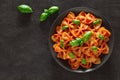 Farfalle, cooked pasta with tomato sauce and basil green leaves, on gray plate, on dark background, top view, space to copy text Royalty Free Stock Photo