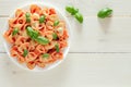 Farfalle, cooked pasta with tomato sauce and basil green leaves, on plate, on white wooden board background, top view, space to Royalty Free Stock Photo