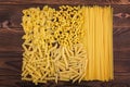 Farfalle, fettuccine, noodles, fusilli and penne rigate. Different kinds of pasta on a wooden background. Tasty Italian cuisine.