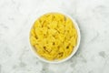 Farfalle italian pasta in white ceramical bowl on gray background, top view