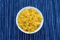 Farfalle macaroni Pasta in a white cup on a striped white blue cloth background in the center. Close-up with the top. Royalty Free Stock Photo