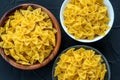 Farfalle macaroni Wooden white and glass bowl with pasta on a textured black background, close-up view from the top.