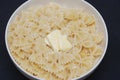 Farfalle Pasta in Bowl with Butter Close Up over Blue Background.