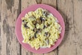 Farfalle pasta in a creamy sauce with champignon mushrooms in a plate on a wooden table.