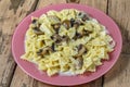 Farfalle pasta in a creamy sauce with mushrooms in a plate on a wooden table.