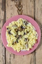 Farfalle pasta in a creamy sauce with mushrooms in a plate on a wooden table.