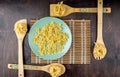 Farfalle pasta on a green plate and fettuccine on bamboo spatulas on a dark wooden background